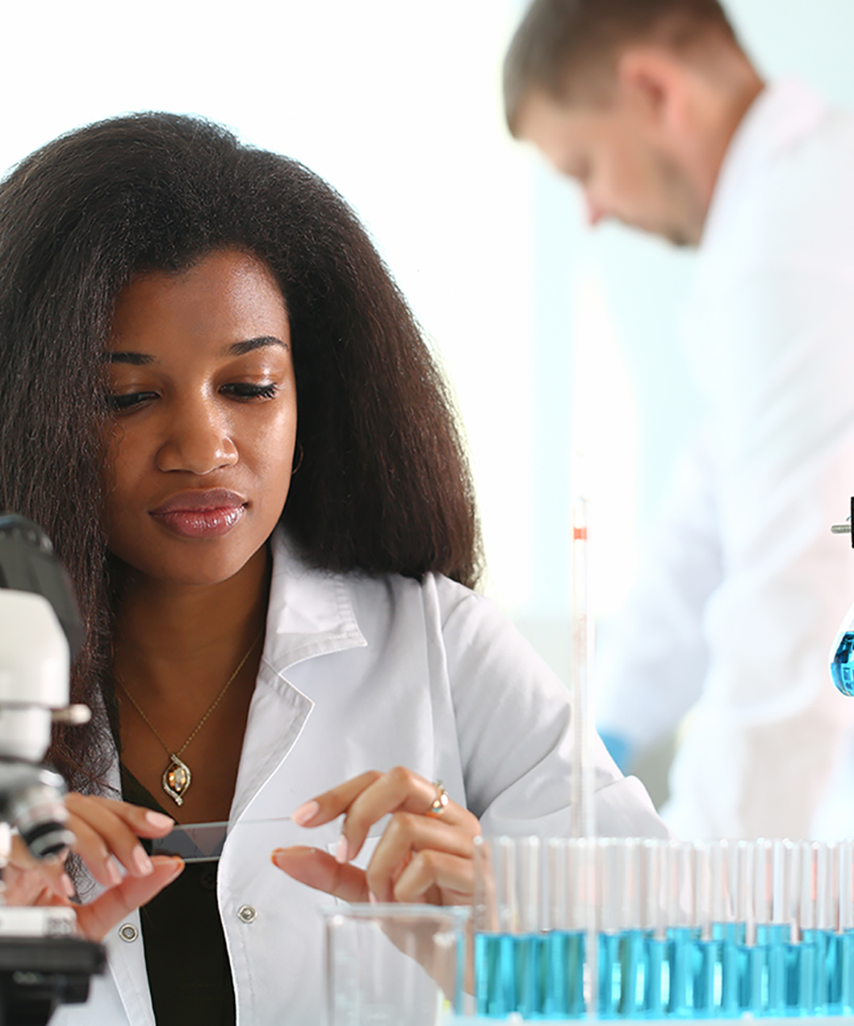 african american woman in labcoat with at microscope
