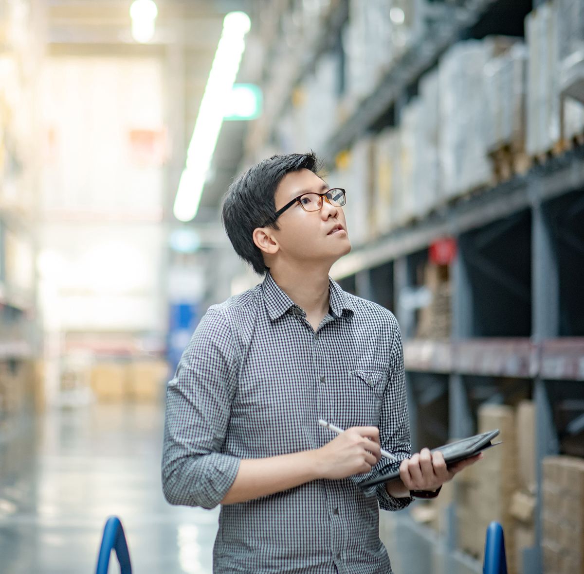 man with glasses in warehouse with clipboard